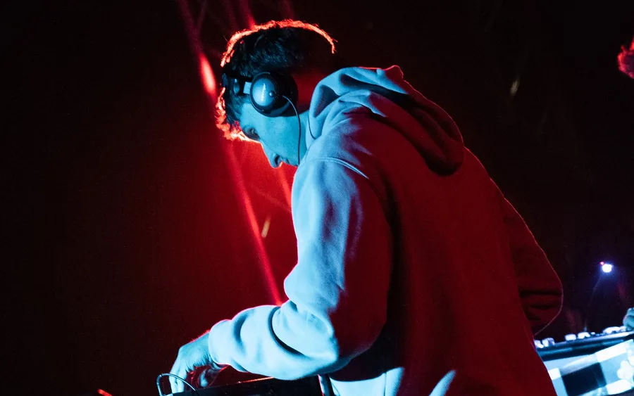 DJ Infinity Vibes za pultem ve světlech klubu